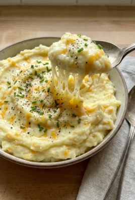 Close-up shot of a spoonful of mashed potatoes showing the cheesy, fluffy texture.