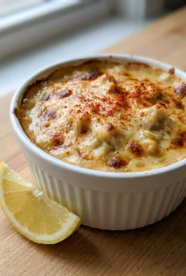 A baked crab imperial in a small casserole dish, topped with paprika.