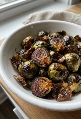A close-up of finished roasted brussels sprouts in a white ceramic bowl.