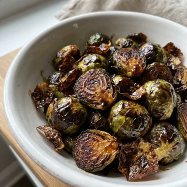 A close-up of finished roasted brussels sprouts in a white ceramic bowl.