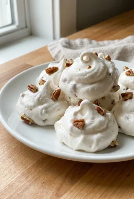 A close-up of a single piece of divinity candy showing its light, airy texture and chopped pecans.