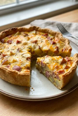 The whole baked ham and cheese quiche, golden brown, sitting on a kitchen counter.