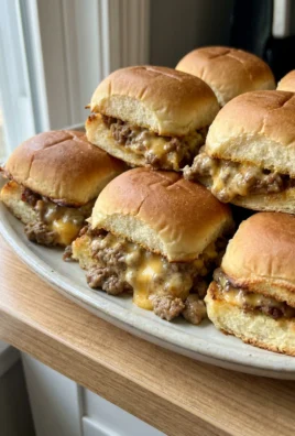 A hand holding a single hanky panky slider made with a pretzel bun.