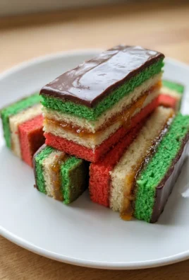 A platter of finished Italian rainbow cookies with a dark chocolate topping.