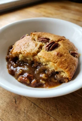 A close-up of a spoonful of pecan pie cobbler, showing the cake and sauce.