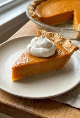 Top-down view of a smooth pumpkin pie filling in an unbaked pie crust.