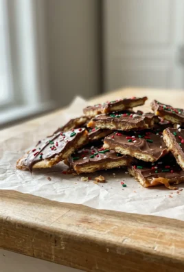 A close-up of a broken piece of saltine chocolate toffee on parchment paper.