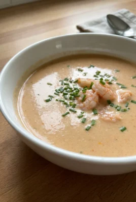 A close-up of a finished bowl of shrimp bisque with pieces of pink shrimp.